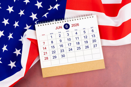 June 2026 Monthly desk calendar and United States of America flag on red wooden.の写真素材