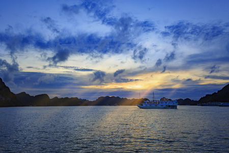 small boat in the middle islands, ha long bay, vietnam in sunsetのeditorial素材