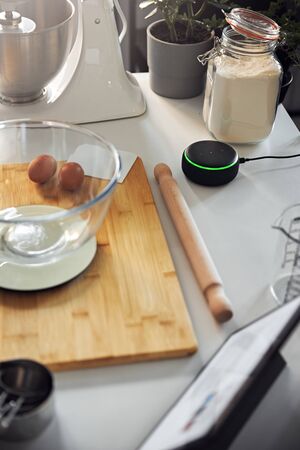 Smart Home Speaker replying to Woman In Home Kitchen Whilst Baking in Lock downの写真素材