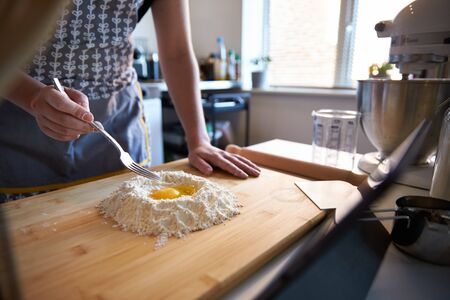 Anonymous Person Making Fresh Pasta At Home in The Kitchen, Watching A Video Recipe with eggs and flour.の写真素材