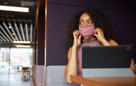 Businesswoman Wearing Mask Working In Socially Distanced Cubicle In Office During Health Pandemicの写真素材