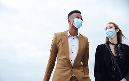 Business Couple Wearing Masks Outside Airport For Business Trip With Luggage During Health Pandemicの写真素材