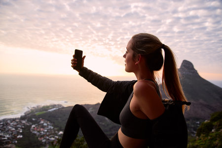 Young woman on vacation wearing backpack walking along coastal path at sunset or sunrise taking...