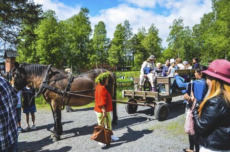 Happy people enjoying horse ride in a park during the swedish mid summer day with colourful clothing...