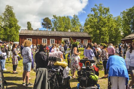 Happy people enjoying and waiting for the swedish mid summer day celebration with colourful clothing and blue sky in the background with trees aroundのeditorial素材