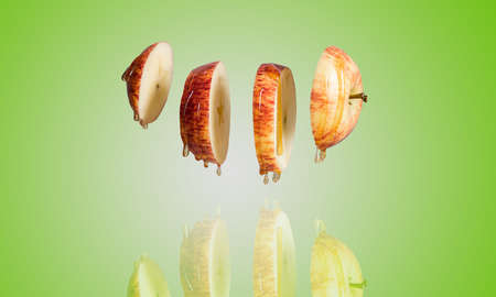 Fresh sliced Red apple and honey dripping in flying food with levitation reflection. Alternative sugar substitute, cold remedy and body strengthening, superfood breakfast green background.の写真素材