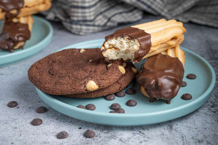 Dark chocolate coated half digestive biscuit with chocolate cookies and chips for loved ones valentines day celebration. Partially eaten with crumbs. side view.の写真素材