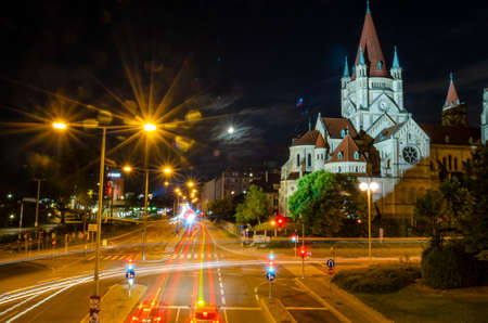 Nightscape cathedral illuminated and car moving light trail long exposure photography in a city landscape during the night timeの写真素材