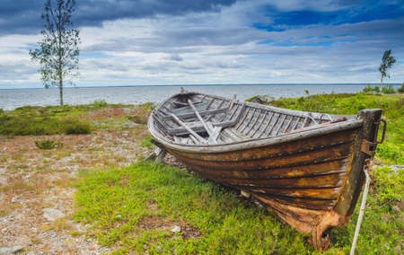 Desserted old boat in a stunning sea coastline with beautiful landscape and panoromic view with horizon and cloud in the blue skyの写真素材