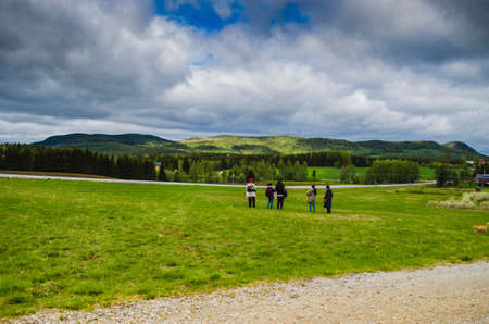 Group of lady tourists enjoying amazing nature landscape with green grass mountain and blue sky covered with clouds in a beautiful dayの写真素材