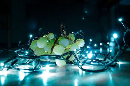 Green fresh grapes on a dark blue background illuminated by lights for nice beatiful background and...