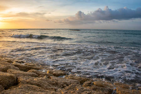 Sunshine from sundown on the stones of the seashore cloudscape during the summer time in Bali,...