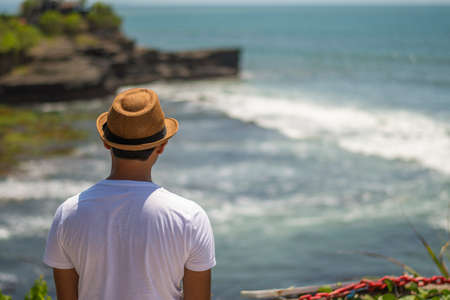A solo male traveller in blue dress is enjoying the beautiful seascape with horizon of Tanh lot in Bali, Indonesiaの写真素材