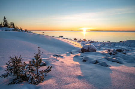 Panoramic sunset through the horizon. Winter wonderland scenery in scenic golden evening light at sunset with clouds and long shadow. tranquil nature copy space background.の写真素材