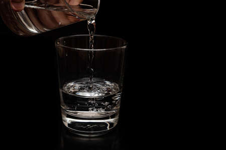 A kid is pouring water in a clear glass with bubble formation for saving water and sustainability of...