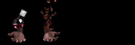 Chemistry round bottom flask and transparent pills dropping on a human scientist hand with black...
