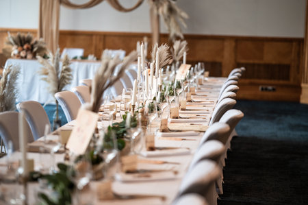 Wedding decor. Beautiful event venue. Indoor round reception table with flowers and chairs. Compositions of flowers and plants in  wooden stands.の写真素材