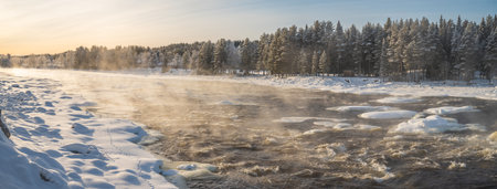 Winter landscape with snowy trees and calm winter river. Winter forest on the river at sunset.