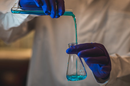 Female chemistry scientist doing experiments in lab. Pipette adding colorful solution in tubes,...