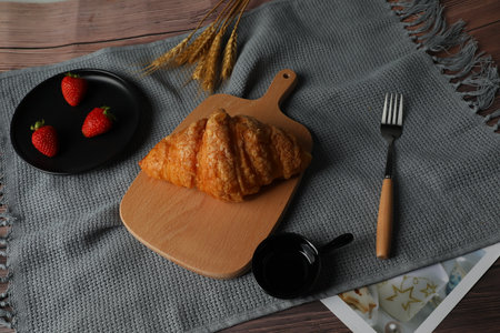 Wooden board with tasty croissant on table, closeupの写真素材