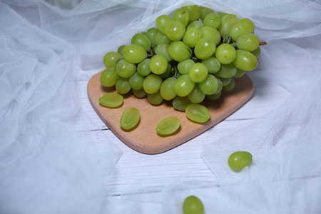 Green grapes on a wooden plate on a white background, close-upの写真素材