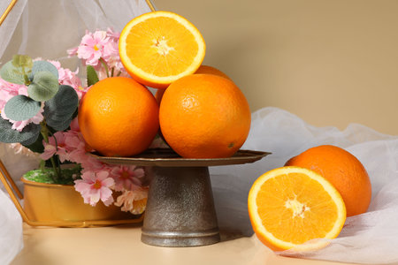 Oranges on a metal stand with a vase of flowers.の写真素材