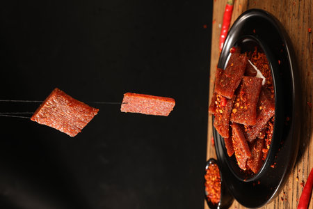 Dried red chili peppers in black bowl on wooden table, closeupの写真素材