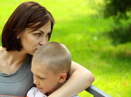 Mother and the son embrace sitting in city parkの写真素材