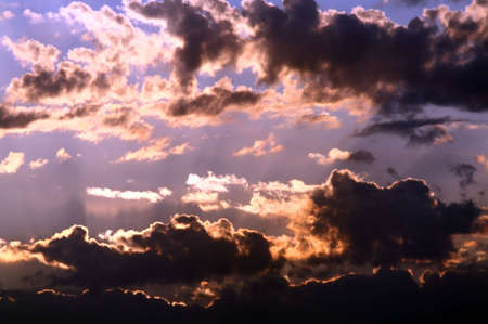 Clouds in the sky in beams of a rising sun