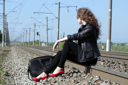 A girl sits on the rail waiting for the trainの写真素材