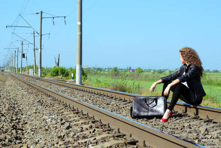 A girl sits on the rail waiting for the trainの写真素材