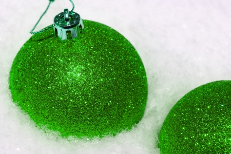 close up of green Christmas balls on white snowの写真素材