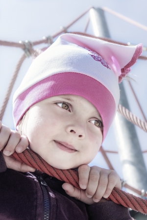 cute young girl on the jungle gym outsideの写真素材
