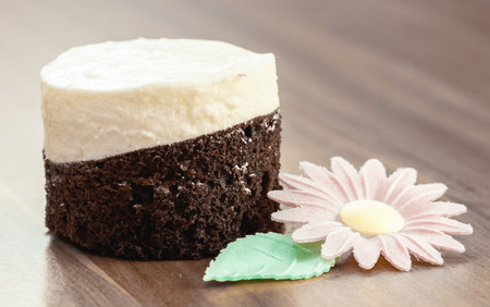 close up of piece of round cake on wood desk with flowerの写真素材