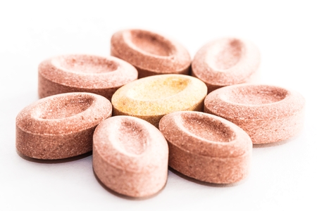 close up of colorful vitamins on white background as flower concept
