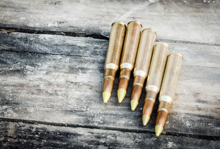 five rifle bullets on old wood desk