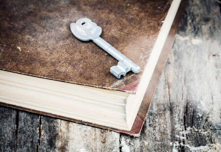 closed old book on grunge wood desk with keyの写真素材
