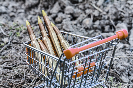 close up of orange chrome shopping cart with bullets on dirty clayの写真素材