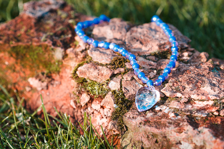 close up of blue previous stone pendant in heart shape at sunset on grunge backgroundの写真素材