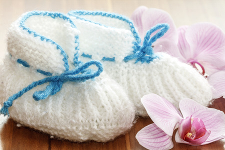small baby blue and white handmade cotton shoes on wooden floor with flowersの写真素材
