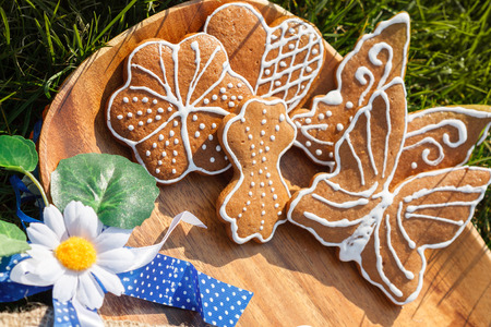 decorated gingerbread on a wooden plate lying in the grass outside with decorative Daisy