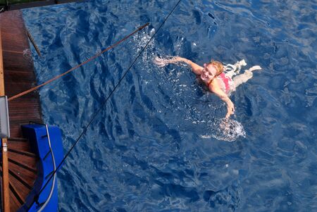 Fit blonde woman enjoying sailing and swimming in the Gulf of Naples basin.の写真素材