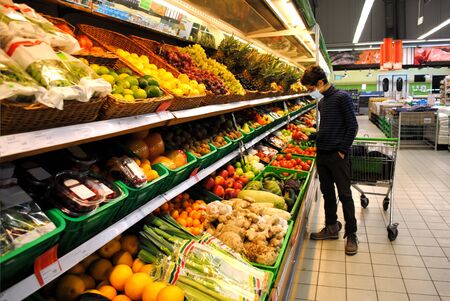 Teenager in respiratory device with shopping cart  in the fruit and vegetable section.の写真素材