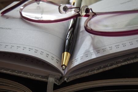 Notebook,pen, and glasses in shallow deep of field.の写真素材