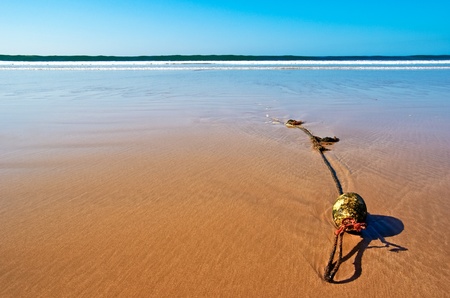 An anchor rope with a buoy at a deserted beach