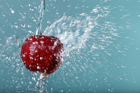 red apple in water drops on green backgroundの写真素材