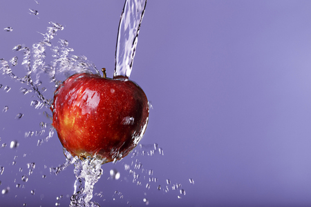 red apple in water drops on purple backgroundの写真素材
