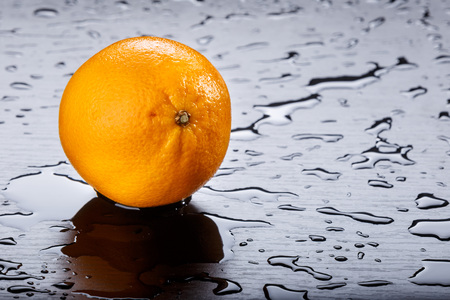 Orange and splash water over black backgroundの写真素材