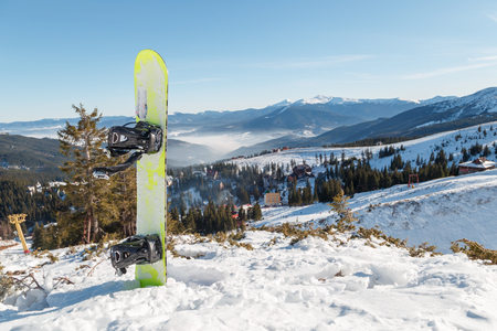 snowboard standing in the snow against the backdrop of the beautiful snow-capped mountainsの写真素材
