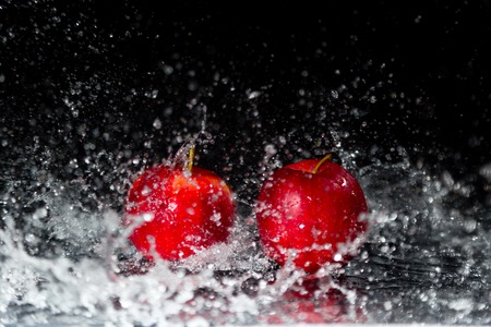 Two red apples in water splash on black backgroundの写真素材